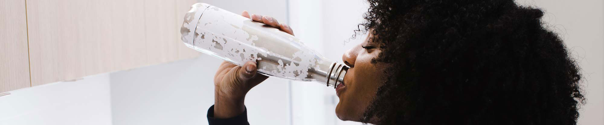 Woman drinking water from a metallic bottle
