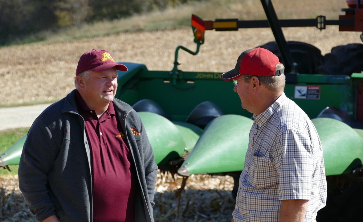 Photo of Brad Carlson talking with a farmer in a field.