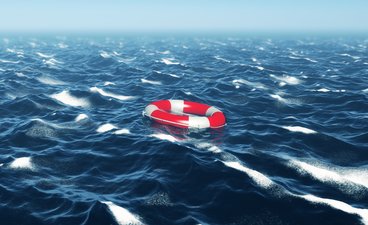Red and white lifebuoy floating in deep blue sea.