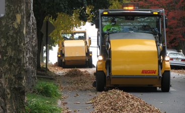 Yellow street sweepers cleaning fallen leaves